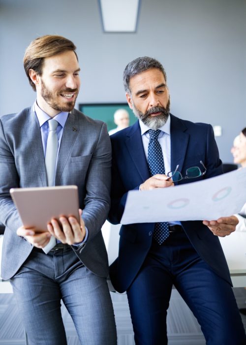 Mature businessman to discuss information with a younger colleague in a modern business office Mature businessman to discuss information with a younger colleague in a modern business lounge
